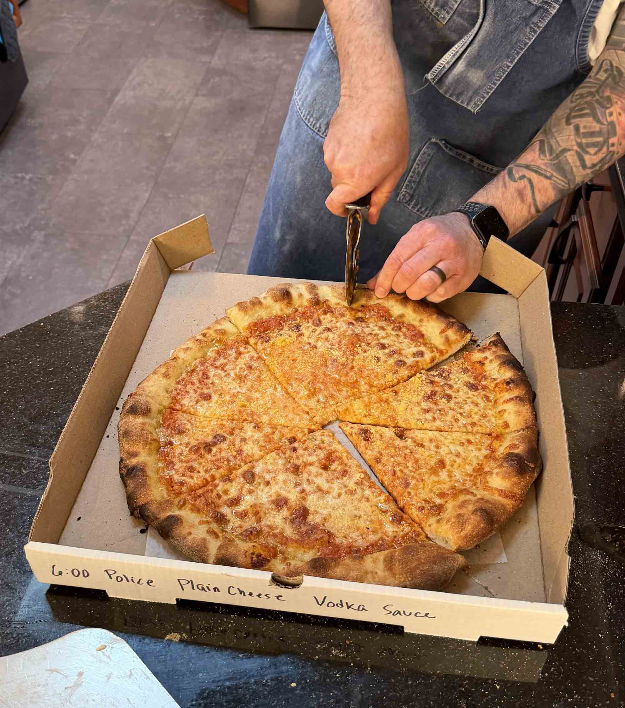A freshly baked pizza being cut and evaluated
